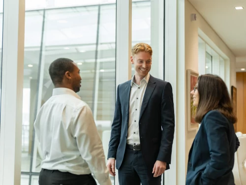 London trainee solicitors talking inside a law firm with natural light and glass walls.