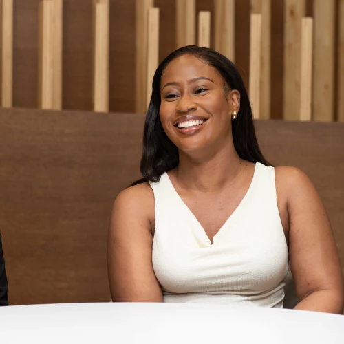 London trainee solicitor smiling during a meeting in a modern office setting.