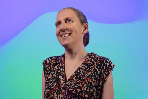 Presenter in front of a colourful backdrop.