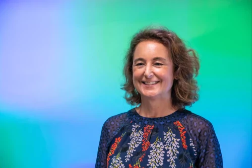 Presenter in front of a colourful backdrop.